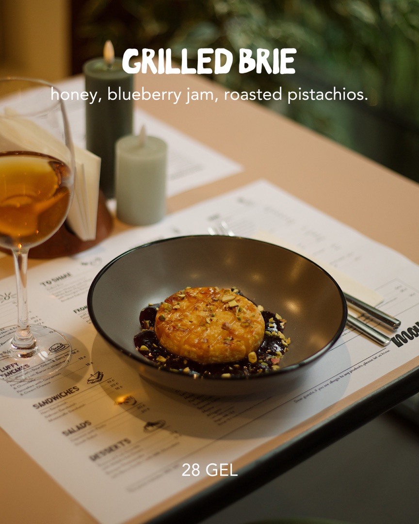 Grilled brie with honey, blueberry jam and roasted pistachios, served with a glass of wine at Maluli
