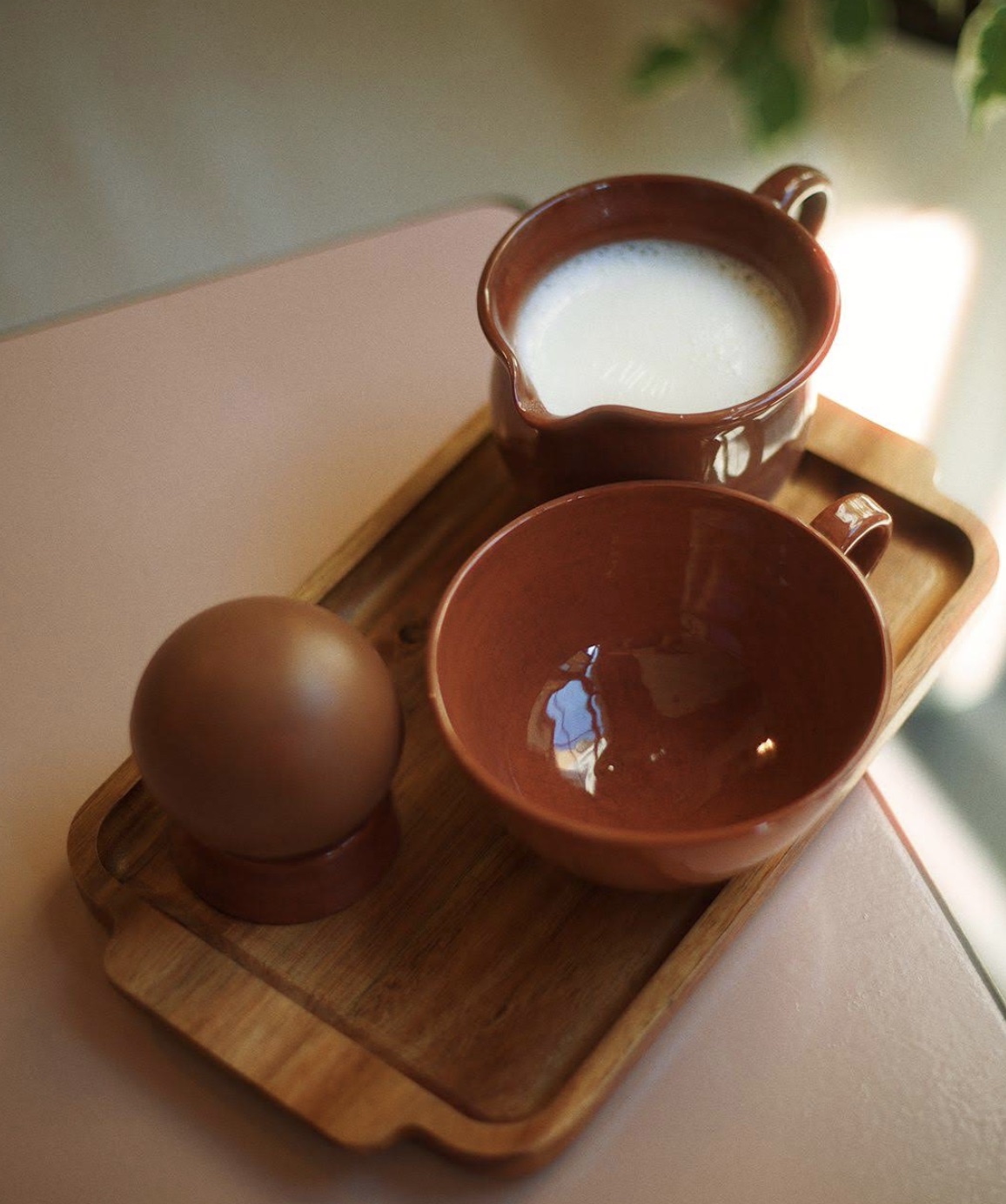 Hot chocolate served on a wooden tray with a chocolate sphere